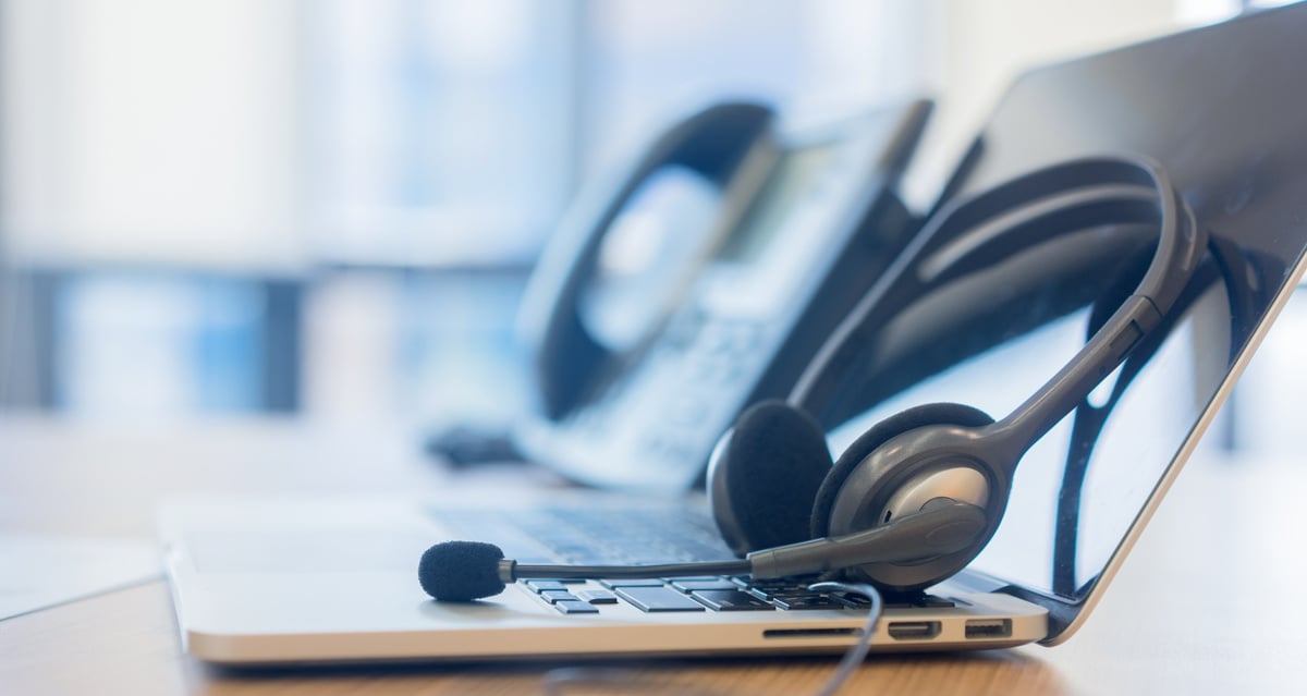 close up focus on call center headset device at VOIP system hanging on monitoring computer at office desk for hotline telemarketing and network operation concept
